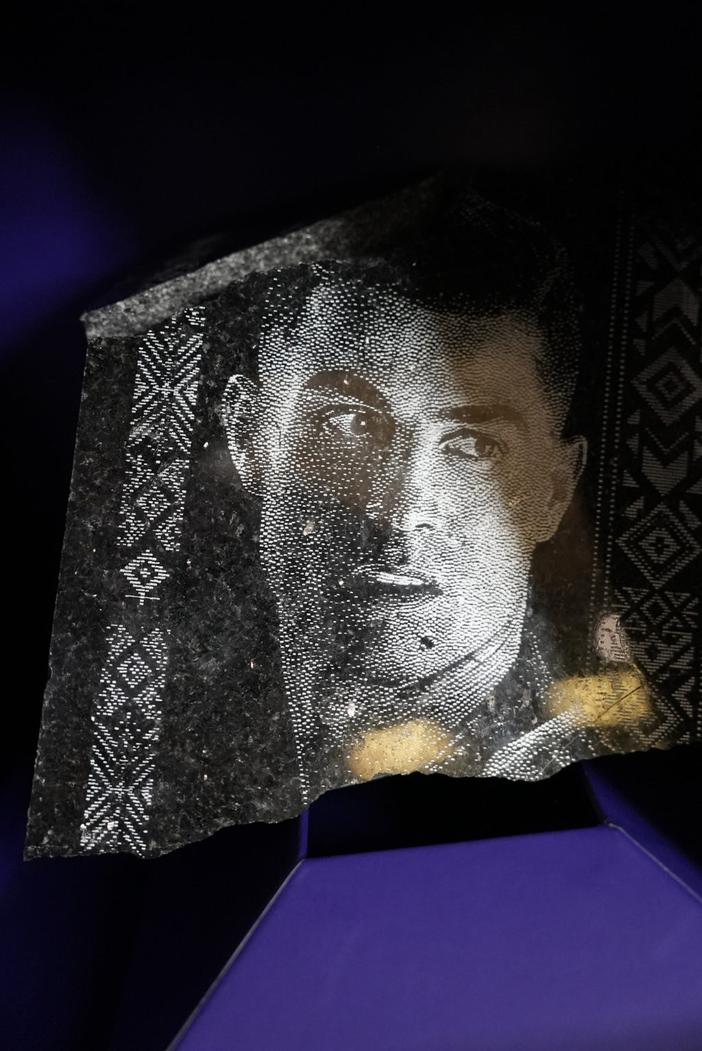 Al Nassr FC black stone engraving laid flat on marble surface — showing Saudi palm crest and natural stone texture