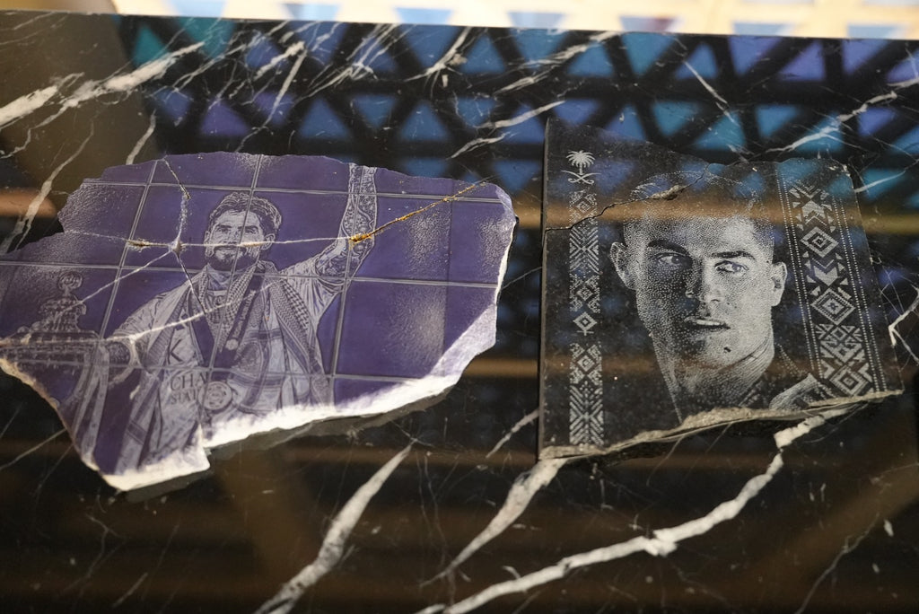 Two Al Nassr FC engraved stone pieces displayed side by side on marble — player portraits with Saudi crest