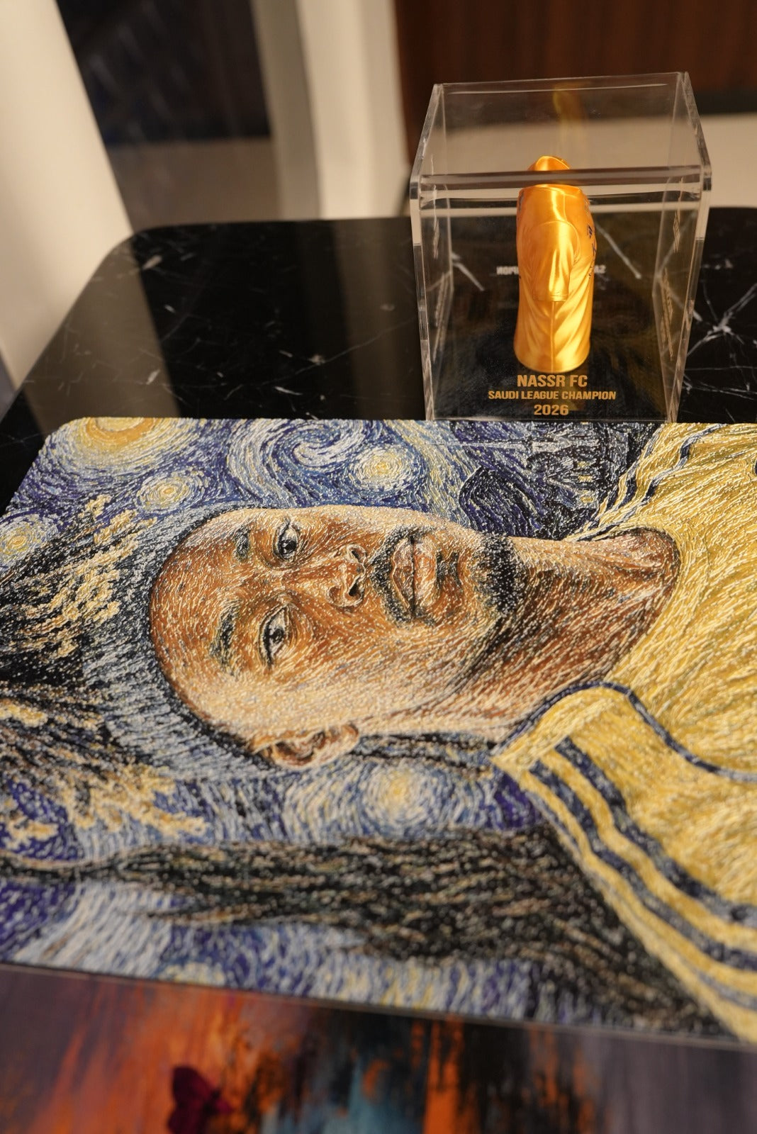 Al Nassr FC embroidered Starry Night displayed on marble surface alongside Saudi League Champion 2026 mini jersey
